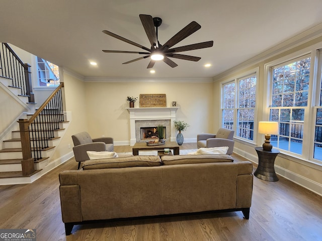 living room featuring hardwood / wood-style floors, ceiling fan, and crown molding