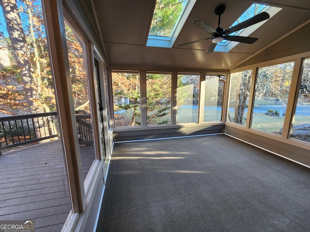 unfurnished sunroom featuring lofted ceiling with skylight, plenty of natural light, and ceiling fan