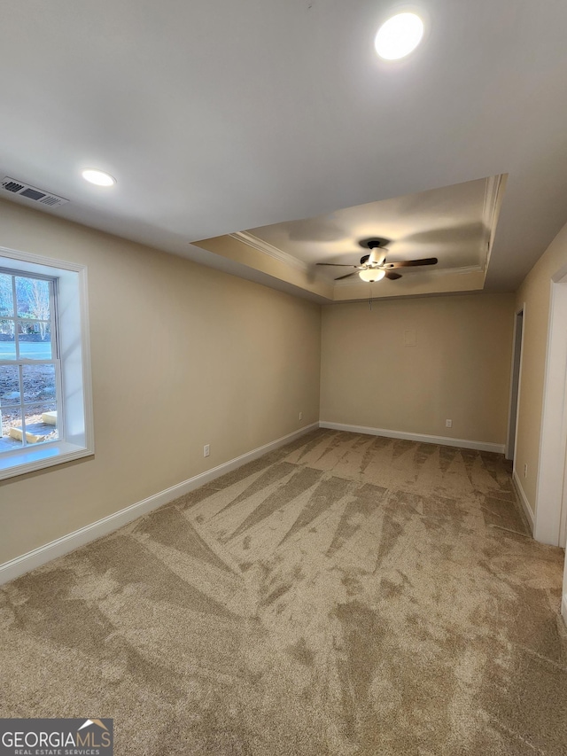 carpeted spare room featuring ceiling fan, ornamental molding, and a tray ceiling