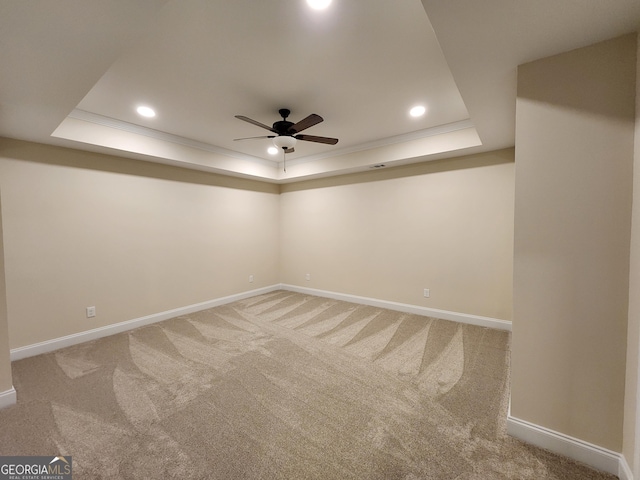 carpeted spare room featuring a tray ceiling, ceiling fan, and ornamental molding