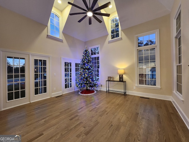 interior space featuring ceiling fan, hardwood / wood-style floors, and a high ceiling