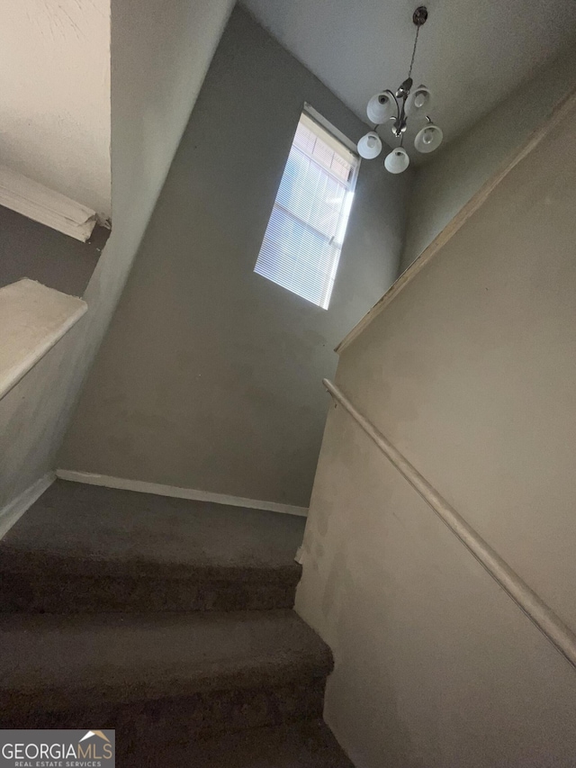 stairs with hardwood / wood-style floors and a chandelier