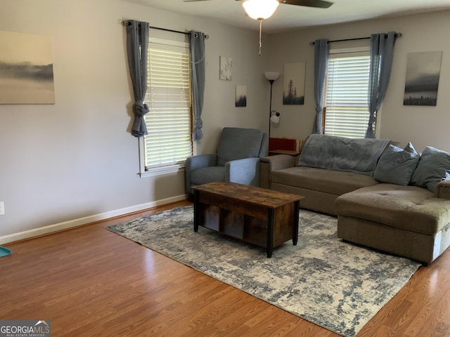 living area with ceiling fan, plenty of natural light, wood finished floors, and baseboards