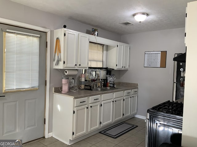 kitchen with white cabinets, stove, plenty of natural light, and sink