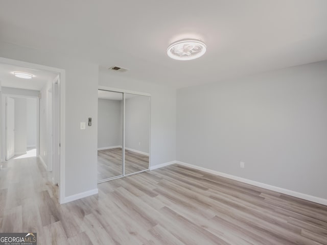 unfurnished bedroom featuring light hardwood / wood-style floors and a closet