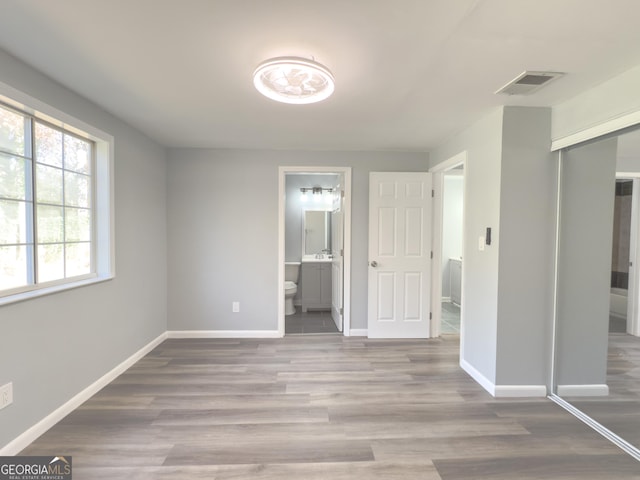 unfurnished bedroom with light hardwood / wood-style floors, connected bathroom, and a closet