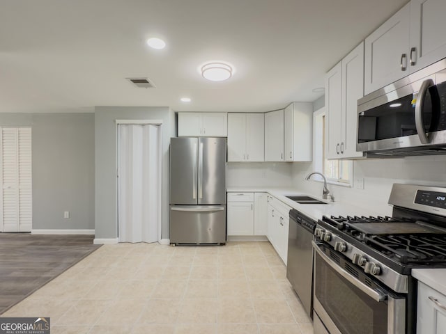 kitchen with sink, white cabinets, light wood-type flooring, and appliances with stainless steel finishes