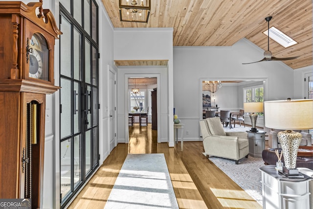 entryway featuring high vaulted ceiling, ceiling fan with notable chandelier, a skylight, light wood-type flooring, and wood ceiling