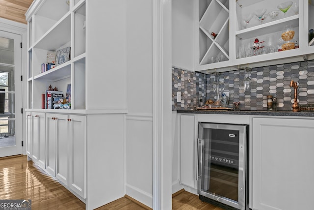 bar featuring white cabinets, wood-type flooring, tasteful backsplash, and beverage cooler