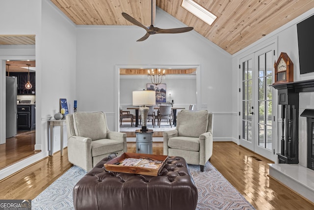 living room with wooden ceiling, high vaulted ceiling, ceiling fan with notable chandelier, light hardwood / wood-style flooring, and a skylight