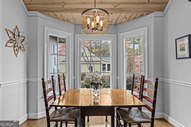 dining space with a notable chandelier, light hardwood / wood-style floors, wood ceiling, and beam ceiling