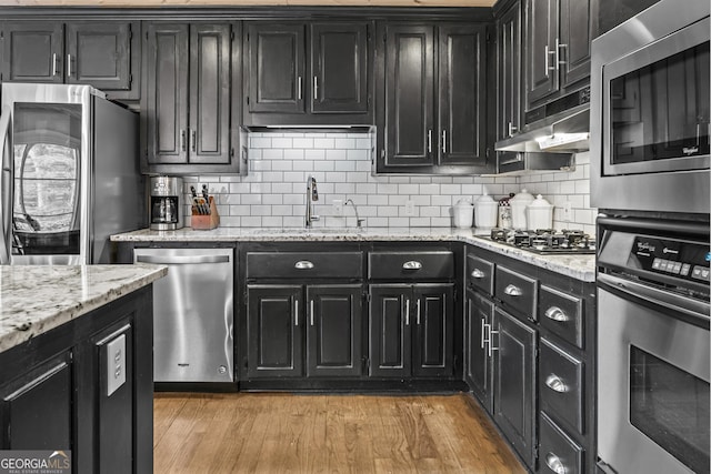 kitchen with decorative backsplash, sink, light wood-type flooring, and appliances with stainless steel finishes