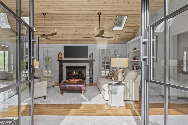 living room with ceiling fan, hardwood / wood-style floors, wood ceiling, and vaulted ceiling with skylight