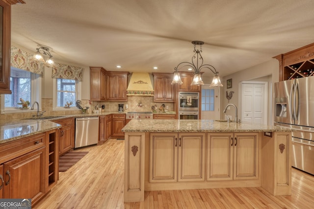 kitchen with custom exhaust hood, pendant lighting, tasteful backsplash, a kitchen island with sink, and appliances with stainless steel finishes