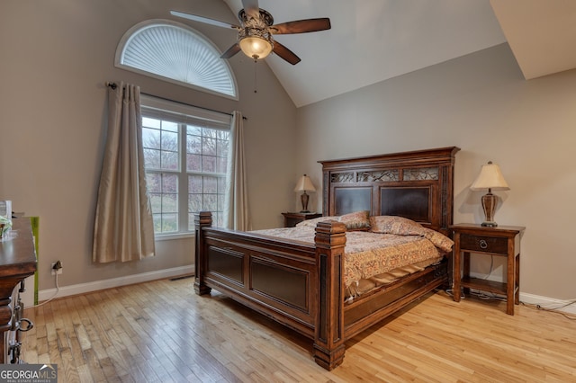 bedroom featuring high vaulted ceiling, ceiling fan, light hardwood / wood-style flooring, and multiple windows