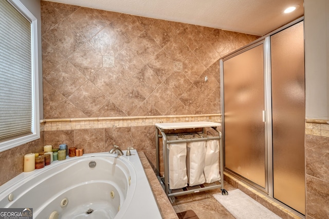 bathroom with tile walls, tile patterned flooring, plus walk in shower, and a textured ceiling