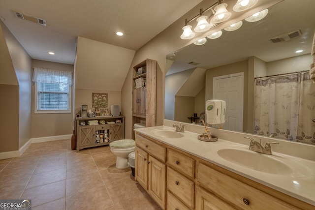 bathroom with toilet, tile patterned flooring, vaulted ceiling, and vanity