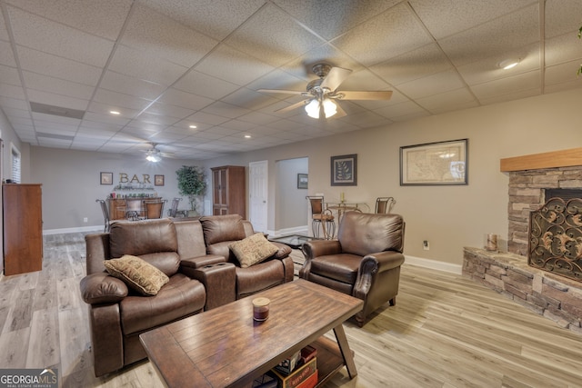 living room with a fireplace, a drop ceiling, ceiling fan, and light hardwood / wood-style flooring