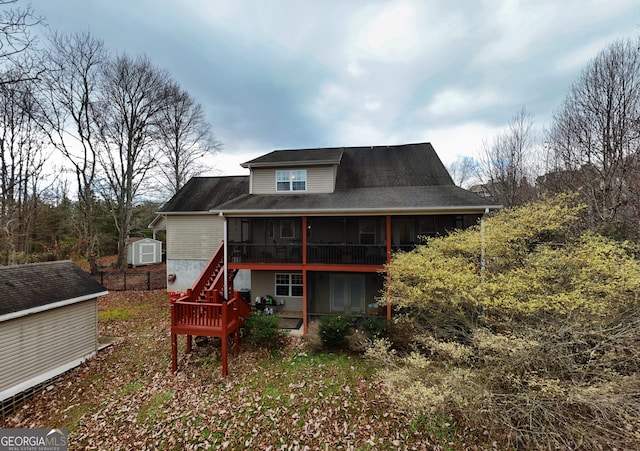 rear view of house featuring a sunroom and a storage shed