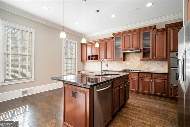 kitchen featuring appliances with stainless steel finishes, a kitchen island with sink, dark wood-type flooring, sink, and pendant lighting