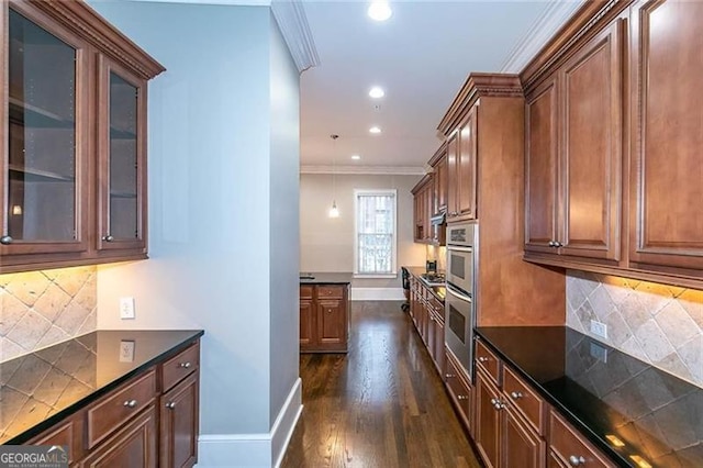 kitchen with dark wood-type flooring, crown molding, pendant lighting, decorative backsplash, and appliances with stainless steel finishes