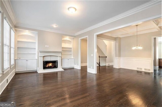 unfurnished living room with dark hardwood / wood-style flooring, ornamental molding, coffered ceiling, built in shelves, and a chandelier