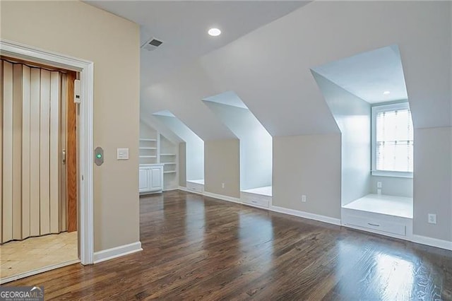 additional living space featuring built in features, dark wood-type flooring, and lofted ceiling