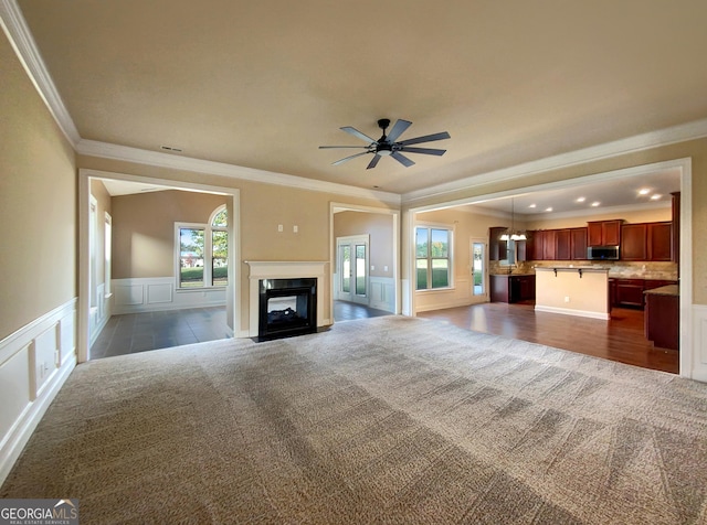 unfurnished living room featuring dark colored carpet and crown molding