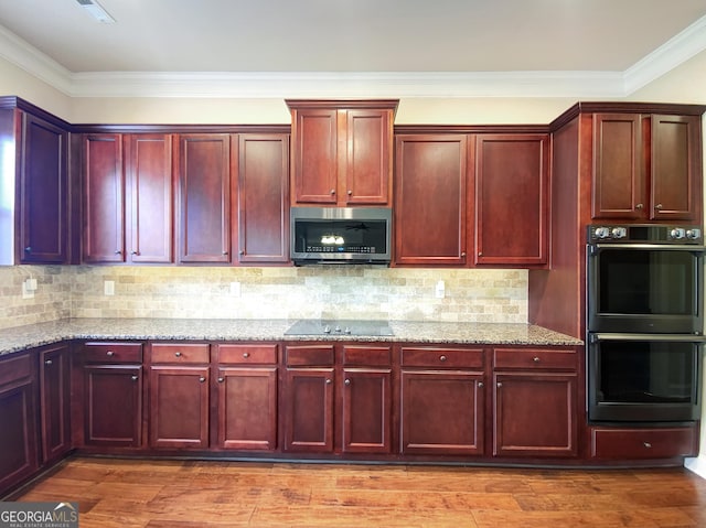 kitchen featuring light stone countertops, hardwood / wood-style floors, and black appliances