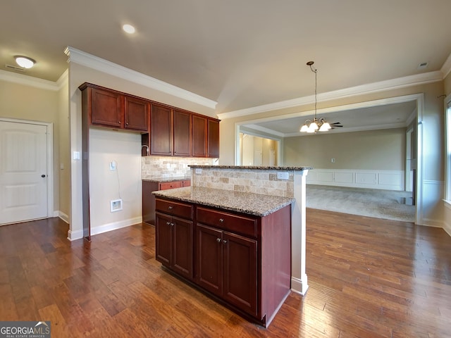 kitchen with light stone countertops, dark hardwood / wood-style flooring, a chandelier, and crown molding