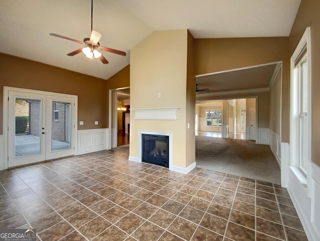 unfurnished living room featuring dark carpet, a wealth of natural light, lofted ceiling, and ceiling fan