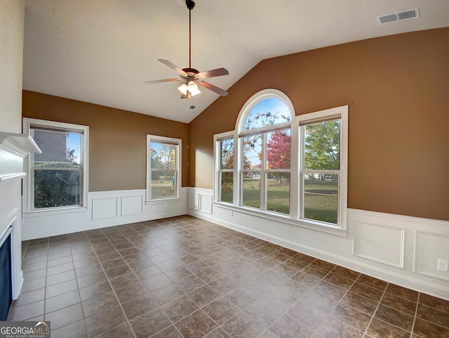 interior space with dark tile patterned floors, a wealth of natural light, lofted ceiling, and ceiling fan