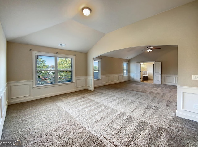 unfurnished living room with ceiling fan, carpet, and vaulted ceiling