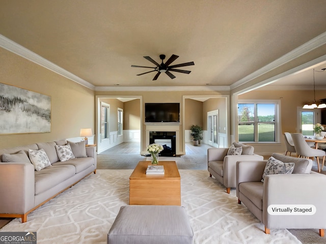 carpeted living room featuring ceiling fan with notable chandelier and crown molding