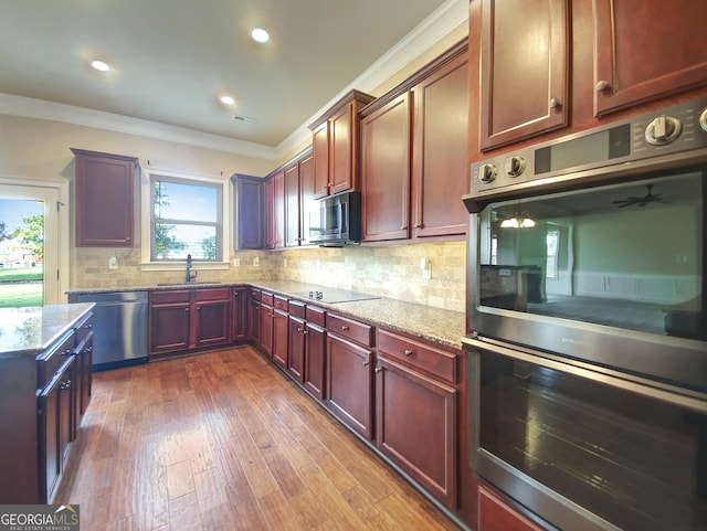 kitchen featuring crown molding, light stone countertops, dark wood-type flooring, and stainless steel appliances