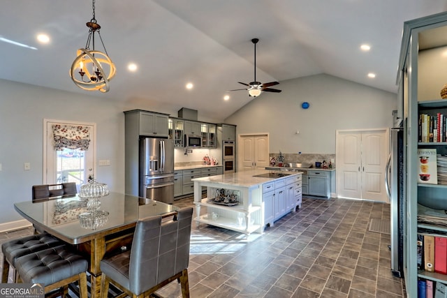 kitchen with a center island, decorative light fixtures, gray cabinets, ceiling fan with notable chandelier, and appliances with stainless steel finishes