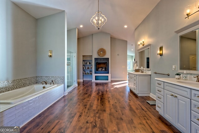 bathroom featuring hardwood / wood-style floors, vanity, vaulted ceiling, independent shower and bath, and a notable chandelier