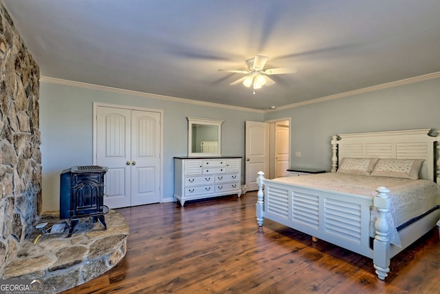 bedroom featuring ceiling fan, a wood stove, dark wood-type flooring, and ornamental molding