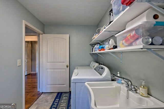 clothes washing area featuring washing machine and dryer, sink, and hardwood / wood-style flooring