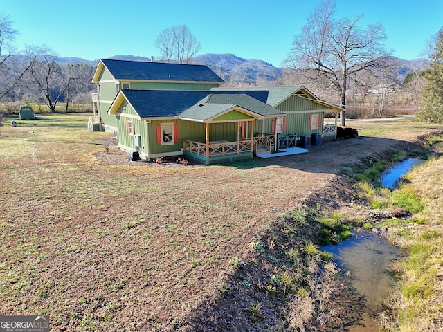 rear view of property featuring a lawn and a mountain view