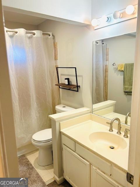 bathroom with tile patterned flooring, vanity, toilet, and walk in shower