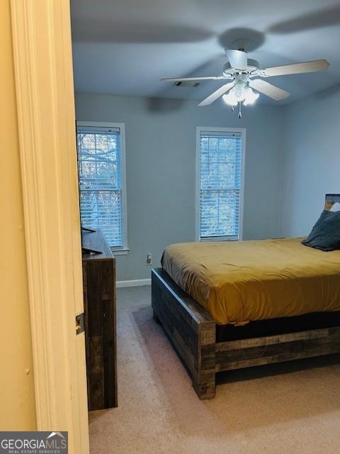 carpeted bedroom featuring ceiling fan and multiple windows