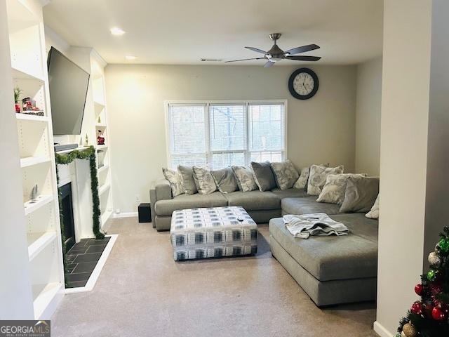 carpeted living room featuring ceiling fan and a tiled fireplace