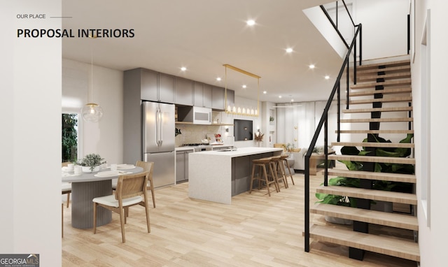 kitchen featuring pendant lighting, a kitchen breakfast bar, light hardwood / wood-style flooring, a kitchen island, and stainless steel refrigerator