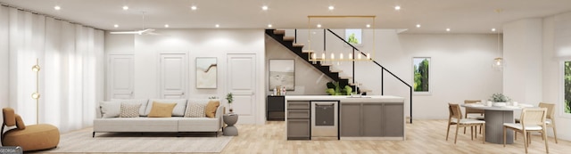 bar with dishwasher, a high ceiling, light hardwood / wood-style flooring, and gray cabinetry