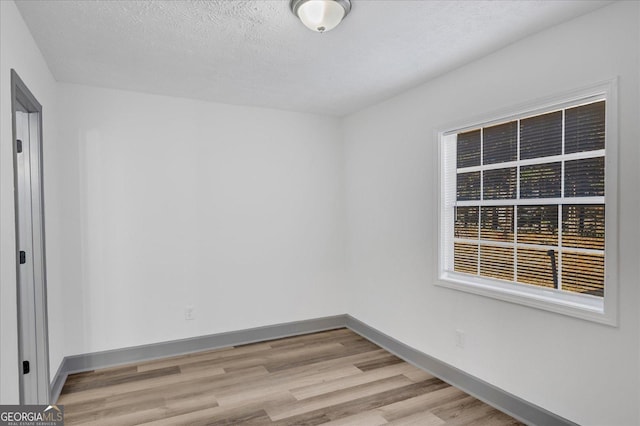 empty room with a textured ceiling and light wood-type flooring