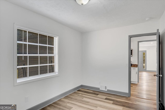 empty room featuring light wood-type flooring and a textured ceiling