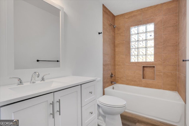 full bathroom featuring hardwood / wood-style floors, vanity, toilet, and tiled shower / bath combo