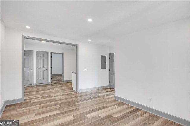 spare room featuring electric panel and light hardwood / wood-style floors