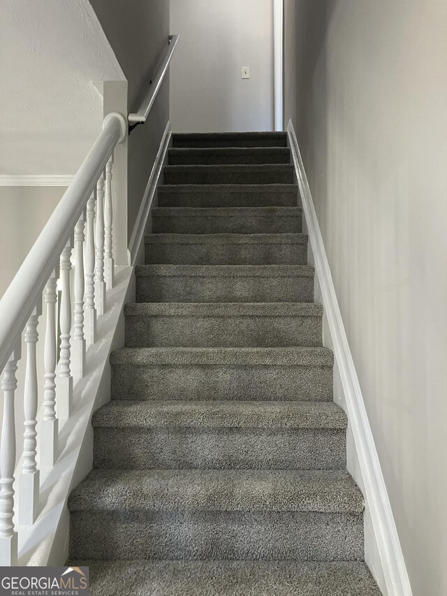 staircase with carpet floors and crown molding